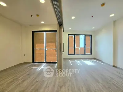 Spacious modern interior with large windows and wooden flooring, perfect for versatile living space.