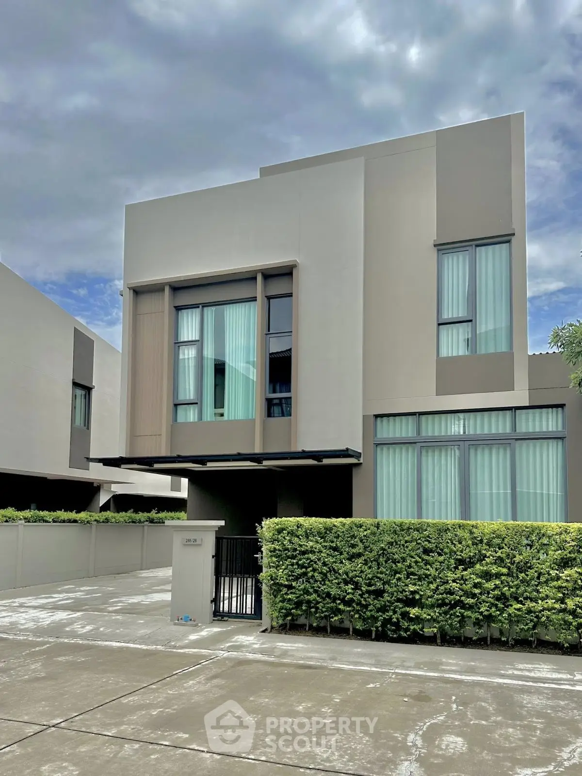 Modern two-story house with sleek design and large windows in a suburban setting.