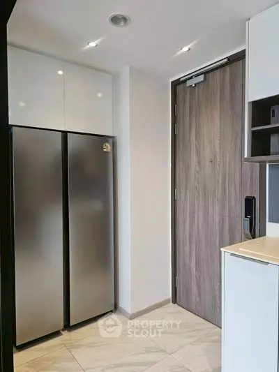 Modern kitchen entrance with sleek stainless steel fridge and wooden door