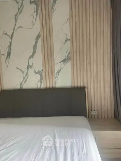 Modern bedroom with stylish marble accent wall and sleek headboard design.