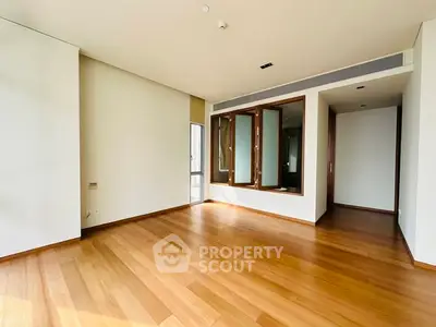 Spacious empty room with wooden flooring and large windows