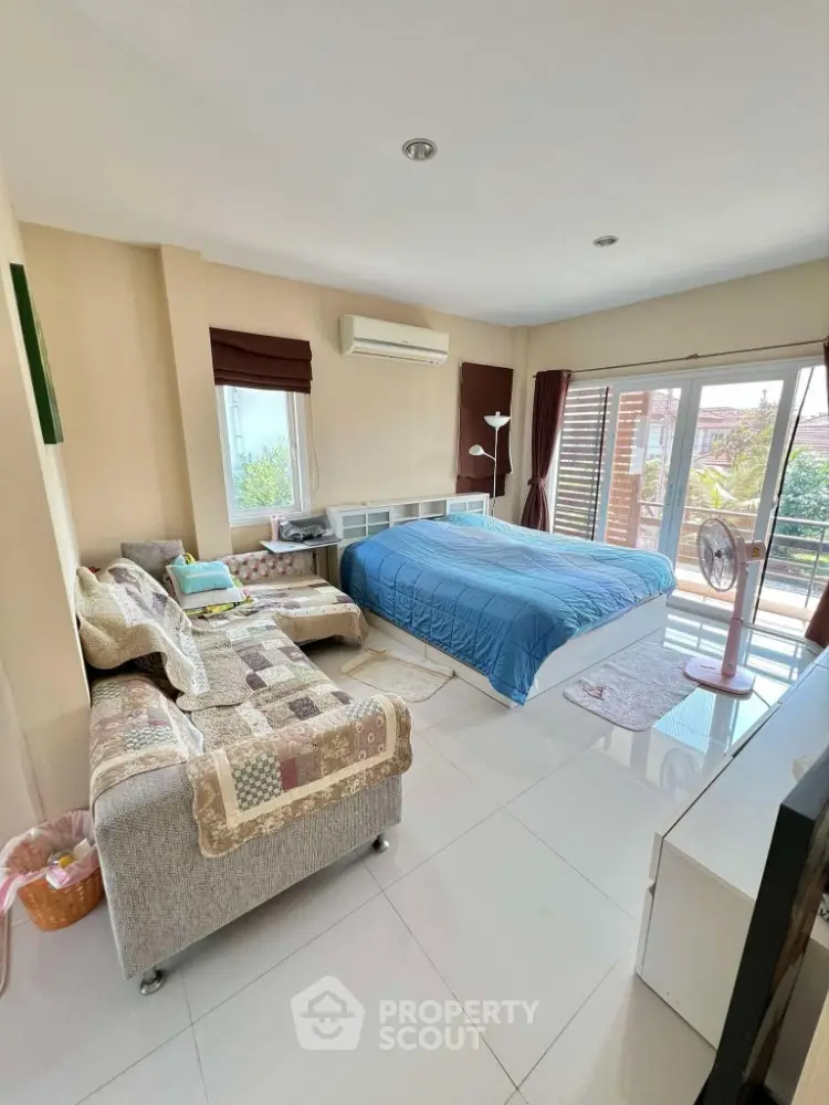 Spacious bedroom with modern decor and large windows offering natural light and garden view.