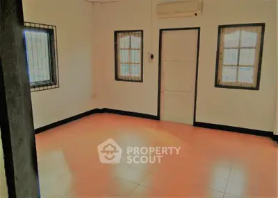 Spacious and well-lit empty room with tiled flooring, multiple windows with security bars, and a neutral color scheme, ideal for customization.