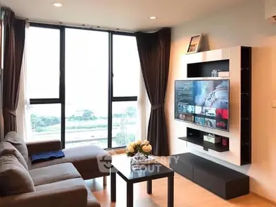 Modern living room with large window and wall-mounted TV, offering a bright and inviting space.