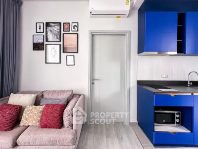 Modern living room with stylish blue kitchen cabinets and cozy sofa, perfect for urban living.