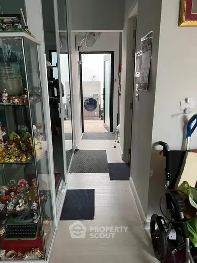 Charming hallway with glass display cabinet leading to a laundry area with modern washing machine.