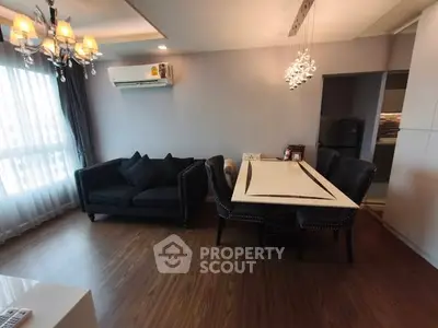 Elegant living room with modern chandelier and stylish dining area, featuring hardwood floors and natural light.