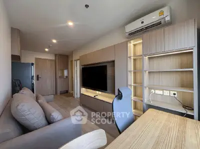 Modern living room with sleek furniture and built-in storage, featuring a large TV and air conditioning.
