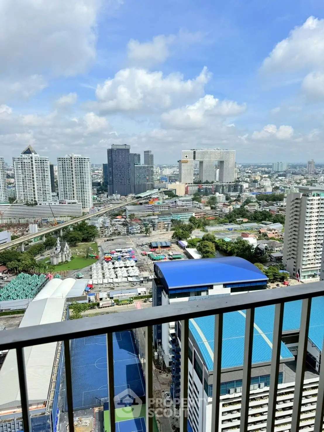 Stunning cityscape view from high-rise balcony with vibrant skyline and clear blue sky.