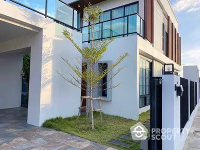 Modern two-story house with sleek design and glass balcony in a serene neighborhood.