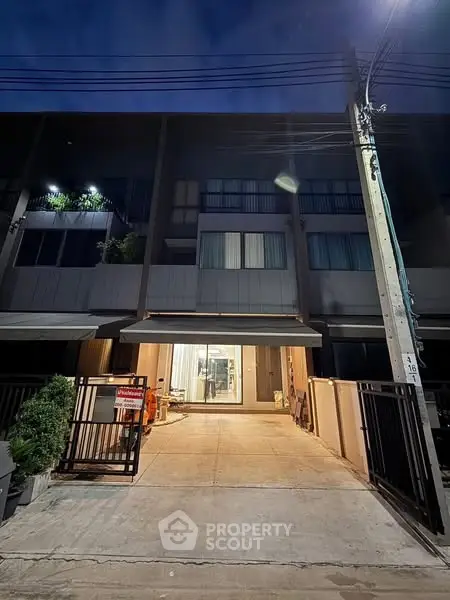 Modern townhouse exterior with gated entrance and night lighting