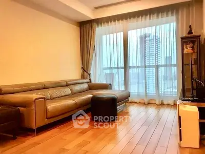Spacious living room with modern leather sofa and large window offering city views