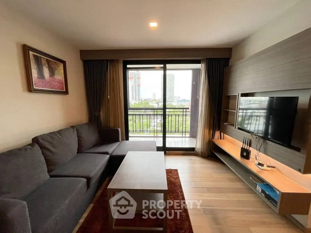 Modern living room with large window and city view, featuring a stylish sofa and entertainment unit.