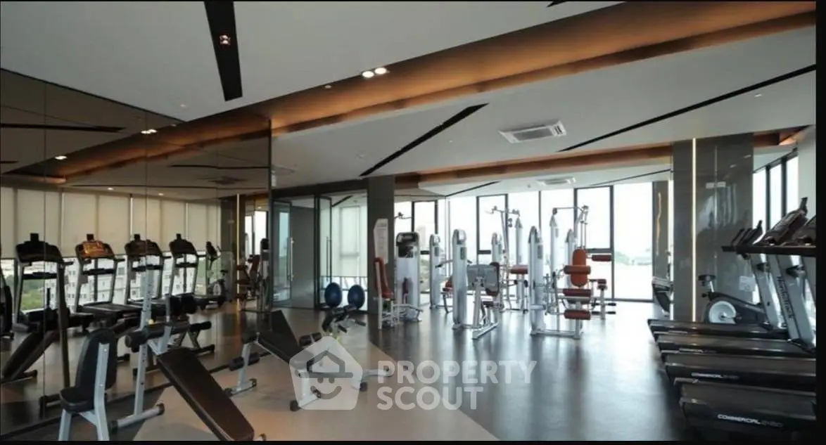 Modern gym with state-of-the-art equipment and panoramic windows in luxury residential building.