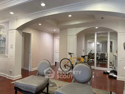 Elegant living room with archways and hardwood floors, featuring a bicycle and stylish seating.