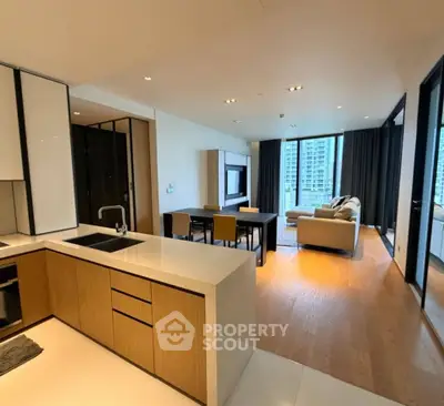 Spacious modern living room with open kitchen and city view, featuring sleek design and natural light.