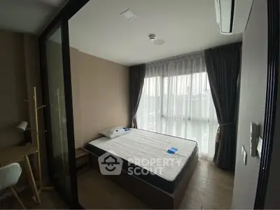 Cozy bedroom with large window and modern furnishings in a stylish apartment.