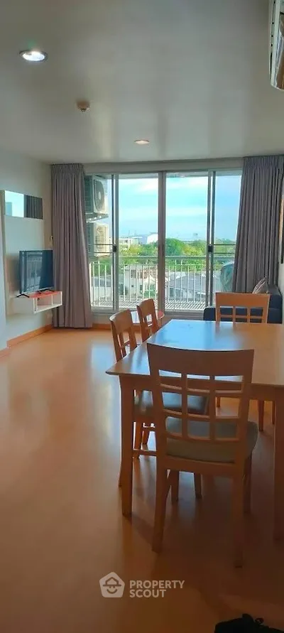 Spacious living room with dining area and balcony view in modern apartment.