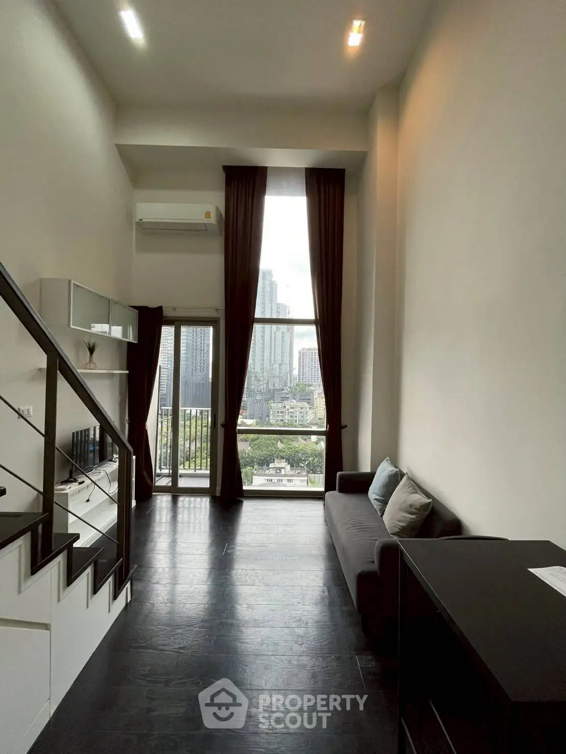 Modern high-ceiling living room with city view and sleek staircase