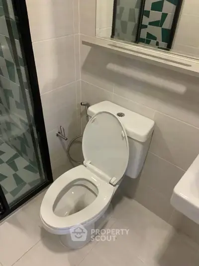 Modern bathroom with sleek toilet and geometric shower tiles