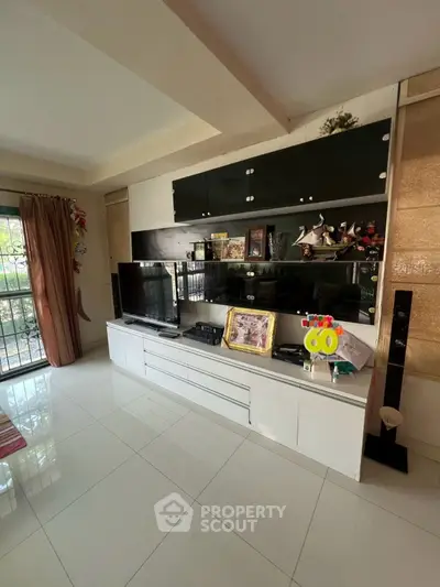 Spacious living room with modern entertainment unit and large window view.