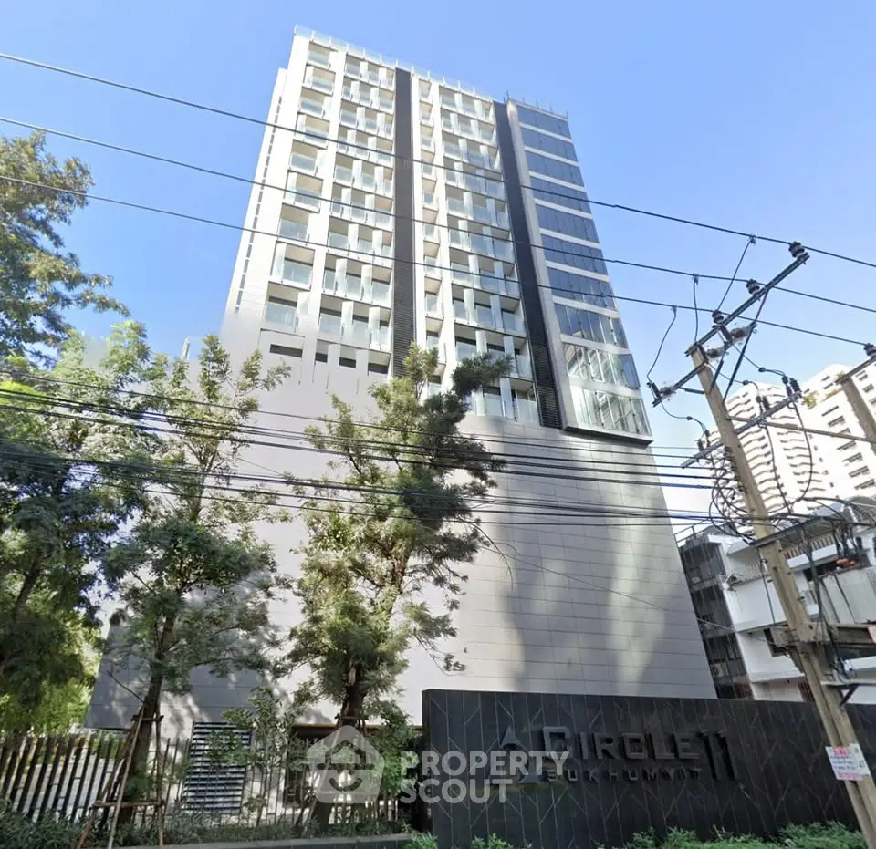Modern high-rise building exterior with sleek design and lush greenery, ideal for urban living.