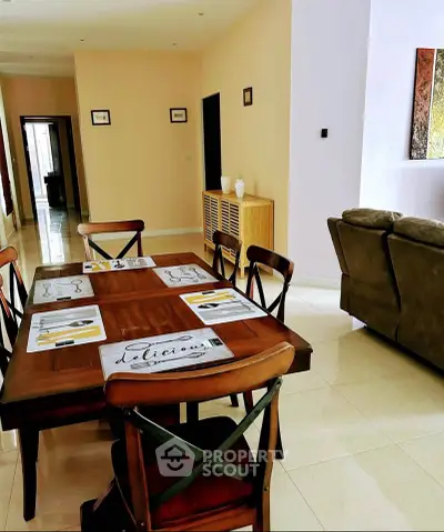 Spacious dining area with elegant wooden table and chairs, adjacent to cozy living room.