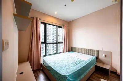 Cozy bedroom with large window and modern furnishings in urban apartment.