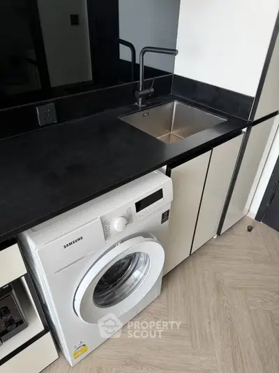 Modern kitchen with sleek black countertop and built-in washing machine