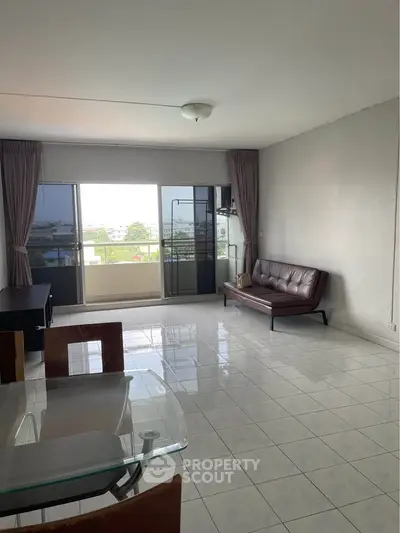 Spacious living room with balcony and modern furniture in a high-rise apartment.