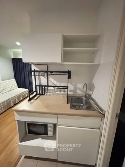Compact kitchen with modern cabinetry and microwave in cozy apartment