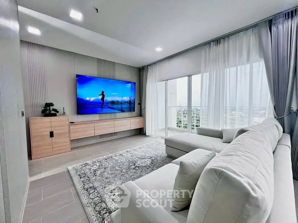 Spacious modern living room with large TV and panoramic city view.