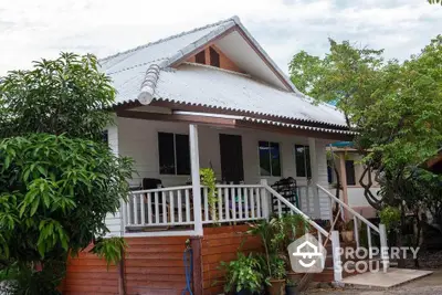 Charming single-story house with a cozy front porch and lush greenery, perfect for serene living.