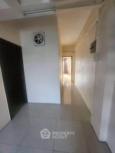 Bright hallway with tiled flooring and a ceiling fan, leading to a sunlit room.