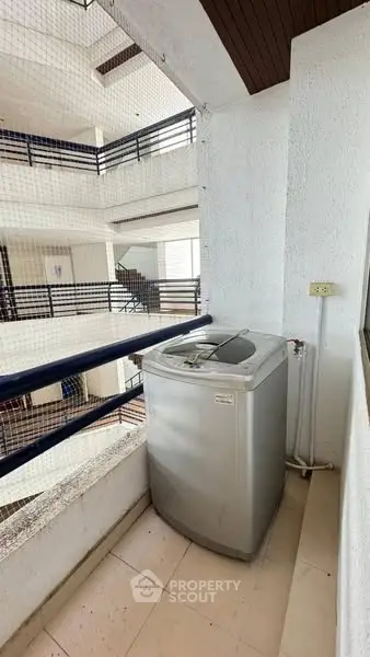 Compact balcony with washing machine in modern apartment complex