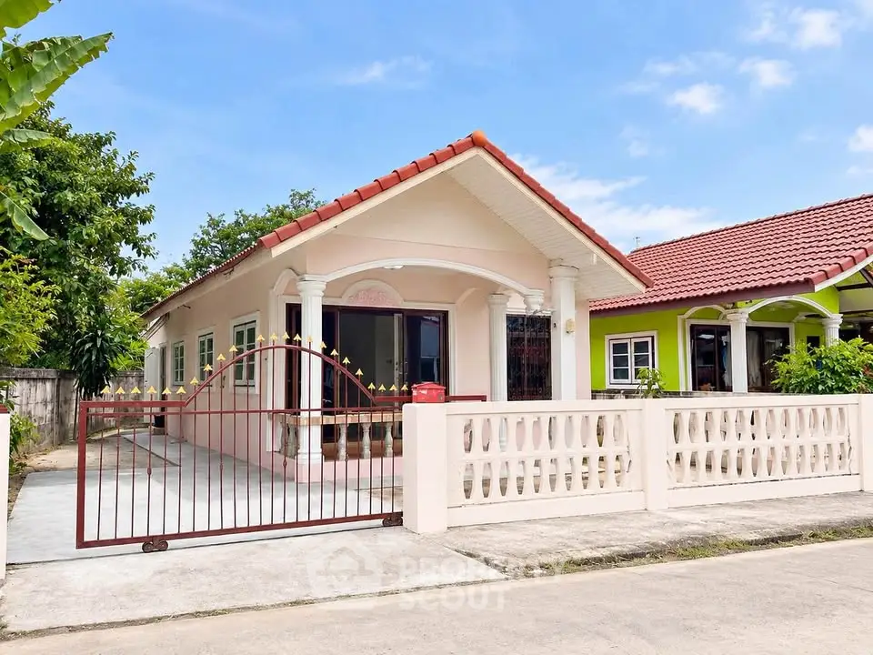 Charming single-story house with red roof and gated driveway in a peaceful neighborhood.
