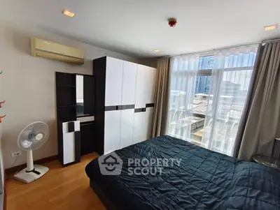 Spacious bedroom with modern wardrobe and large window offering city views.
