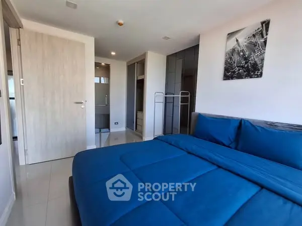 Modern bedroom with blue bedding and sleek design, featuring ample closet space and stylish decor.