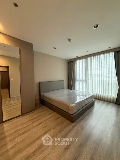 Spacious bedroom with large windows and modern decor in a luxury apartment.