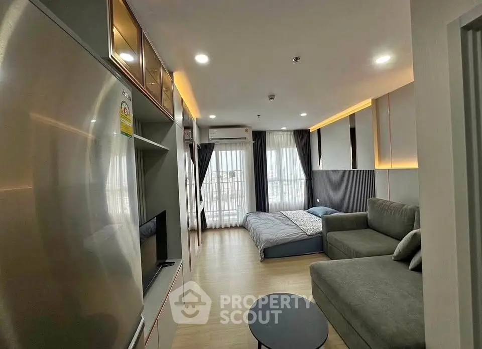 Modern studio apartment with cozy living area and bed, featuring sleek design and natural light.