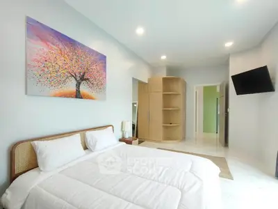 Spacious bedroom with modern decor and vibrant artwork, featuring a cozy bed and ample storage space.