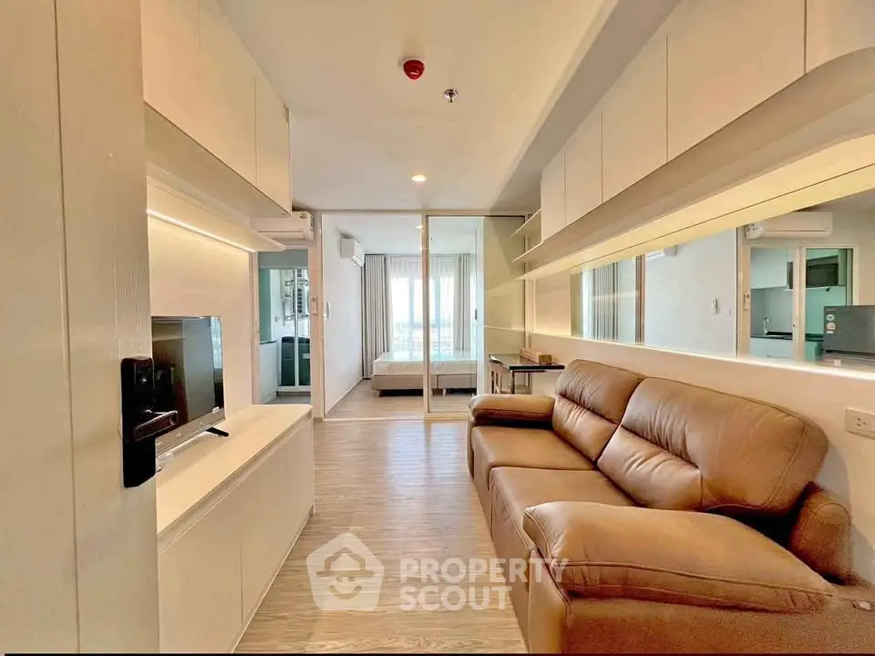 Modern living room with leather sofa and sleek TV unit, featuring a spacious open layout and natural light.
