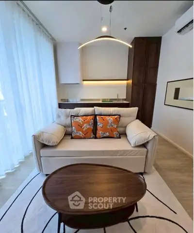 Modern living room with cozy sofa, stylish decor, and open kitchen layout in a bright apartment.