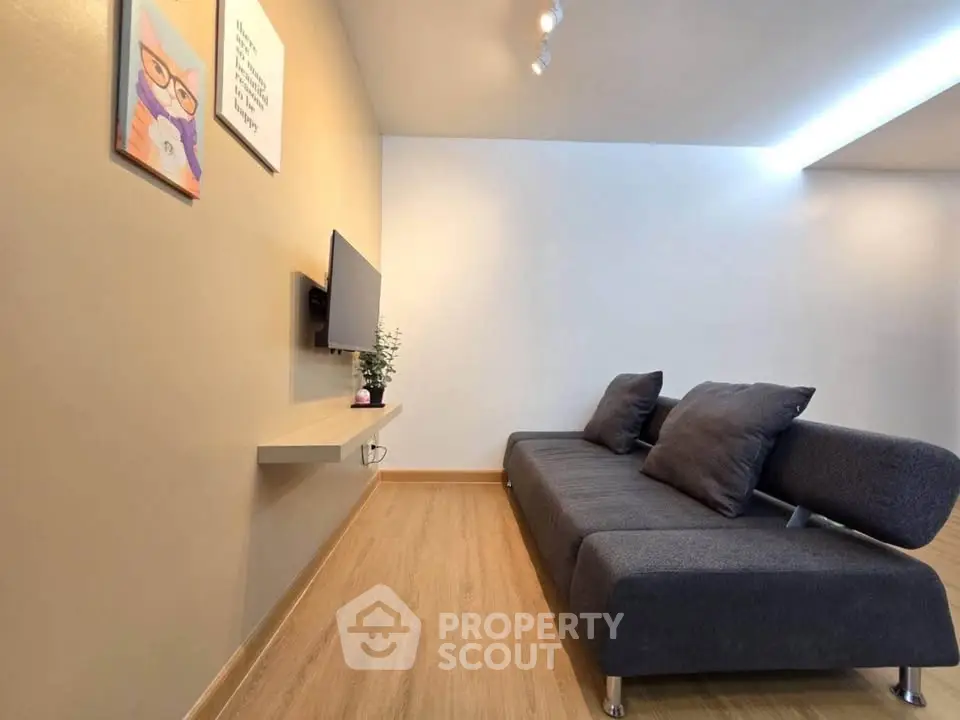 Modern living room with sleek sofa and wall-mounted TV, featuring minimalist decor and warm wooden flooring.