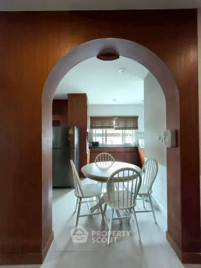 Charming kitchen with wooden archway and cozy dining area, featuring modern appliances and natural light.