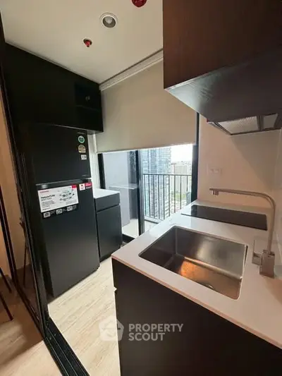 Modern kitchen with sleek black appliances and balcony view