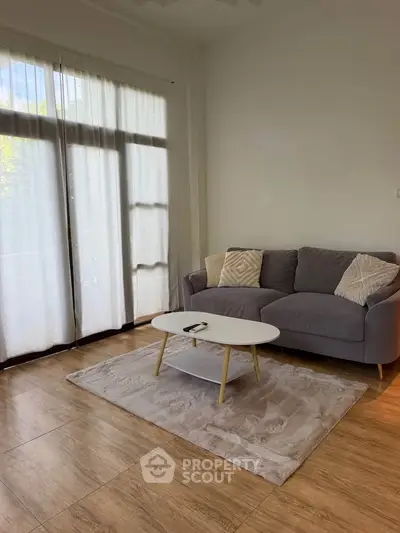 Modern living room with cozy gray sofa, stylish coffee table, and large window for natural light.