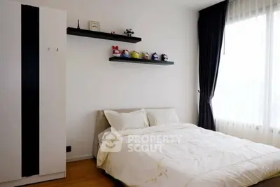 Cozy bedroom with modern decor and ample natural light from large window.