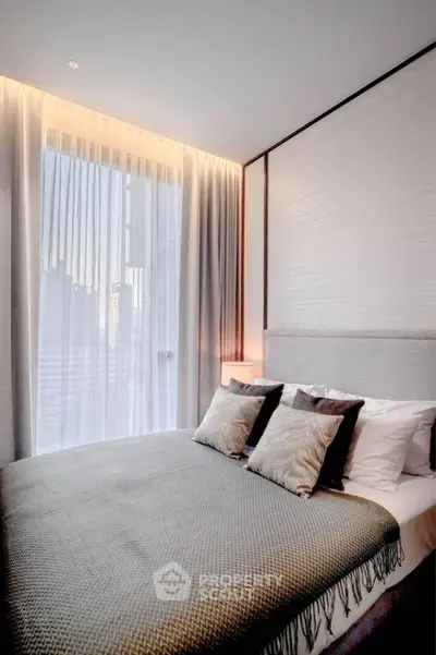 Luxurious modern bedroom with elegant decor and large window offering natural light.