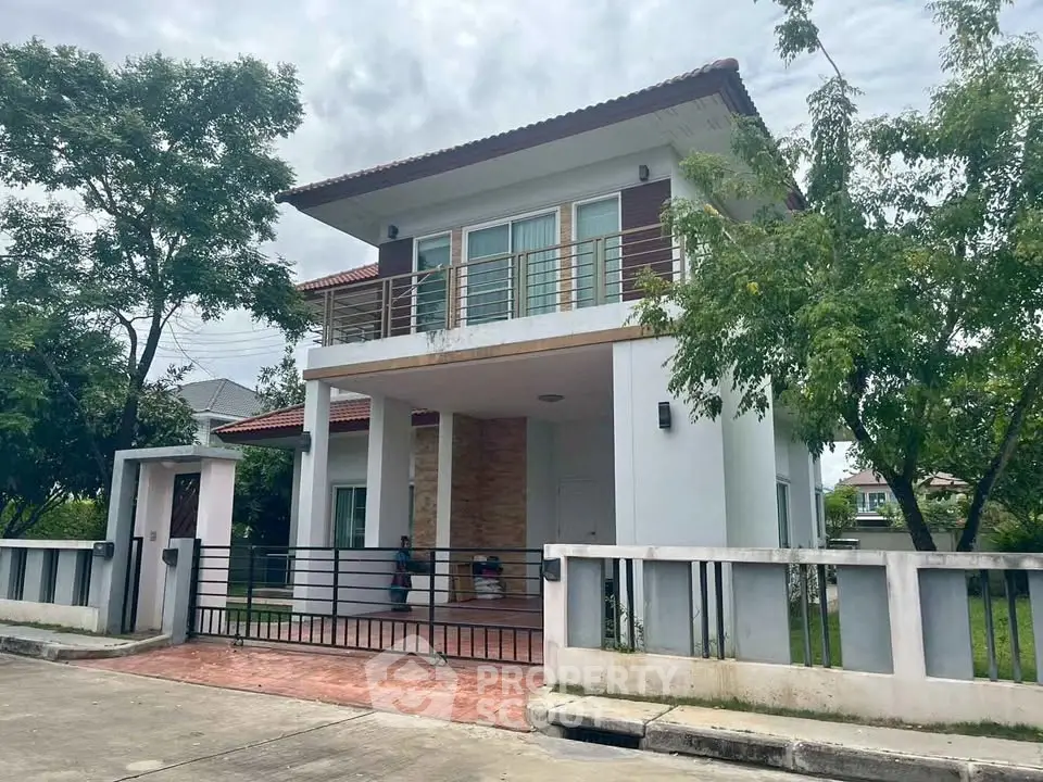Charming two-story house with spacious balcony and lush greenery in a serene neighborhood.